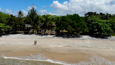 People-explore-exotic-sandy-beach-in-Madagascar-holiday-resort,-Drone-wide-view