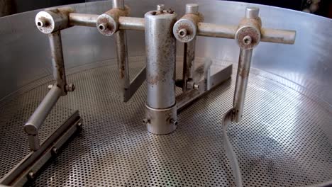Closeup-of-stainless-steel-drum-style-coffee-roaster-machine-slowly-turning-after-roasting-a-fresh-batch-of-coffee-beans