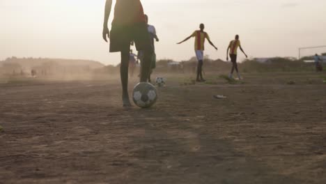 A-number-of-black-males-play-soccer-in-a-dirt-field