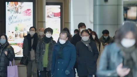Pendler-Verlassen-Den-Bahnhof-Shinagawa-Mit-Gesichtsmaske-Als-Vorbeugende-Maßnahme-Wegen-Des-Neuen-Covid-19-Stammes-In-Tokio,-Japan