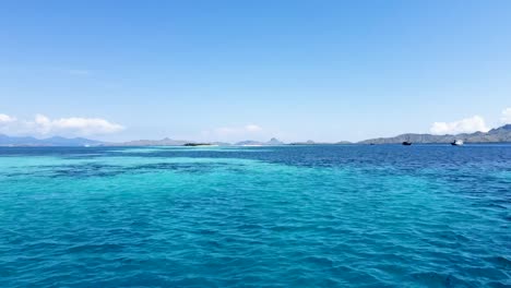 Agua-Turquesa-Entre-Las-Islas-Komodo-Y-Padar,-Indonesia-Con-Barcos-Estacionados-A-La-Derecha,-Plataforma-Rodante-Aérea-En-Toma.
