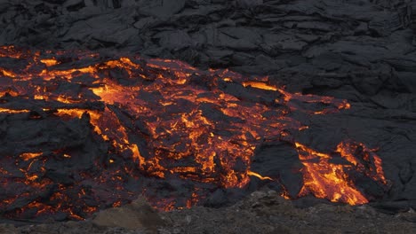 Glowing-stream-of-incandescent-lava-flowing-in-desolated-landscape