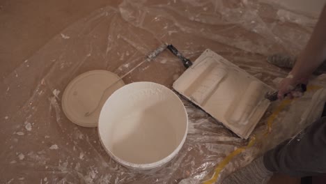 person-taking-paint-with-roller-for-wall-white-painting