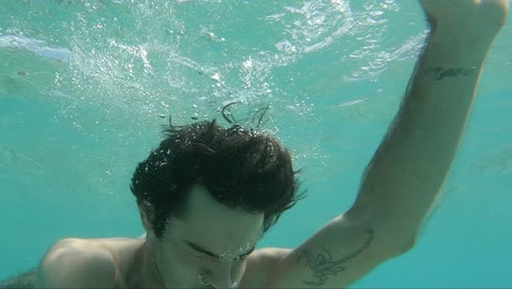 Man-with-brown-hair-dunks-himself-under-the-surface-of-the-oceans-water