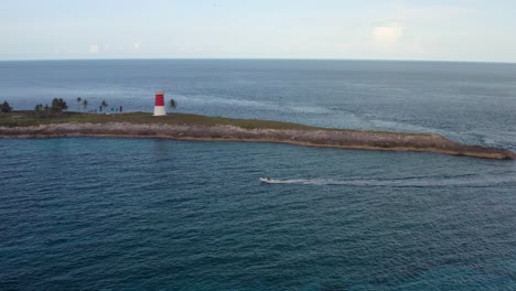 Aerial-of-Speedboat-Sailing-by-the-Cape-and-Lighthouse-on-Bimini,-Bahamas
