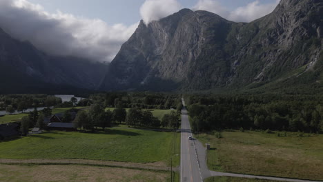 Luftaufnahme-Eines-Autos,-Das-Durch-Eine-Straße-Mitten-Im-Grünen-Tal-Und-Ackerland-In-Romsdalen,-Norwegen-Fährt-–-Drohnenaufnahme