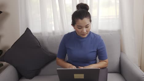 Asian-businesswoman-authentic-shot-using-a-laptop-to-work-from-home-happily