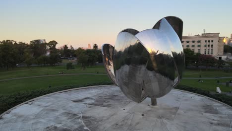 Aerial-circular-pan-twice-shot-of-modern-chrome-Floralis-Generica-art-installation-in-urban-park-Plaza-of-the-United-Nations-at-Recoleta-neighborhood-at-downtown-Buenos-Aires
