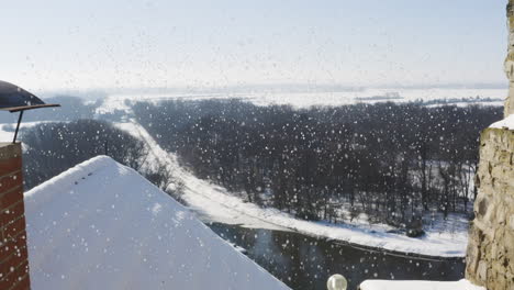 Ziegelschornstein-Auf-Einem-Dach-über-Einem-Fluss-Und-Wäldern,-Fallender-Schnee,-Winter