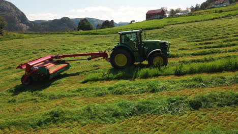 Agricultor-En-Tractor-Trabajando-En-Campos-Cortando-Hierba-Para-Ensilaje-En-Un-Día-Soleado-En-Noruega