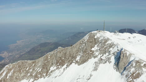 Aerial-of-tall-radio-tower-on-top-of-snow-covered-mountain