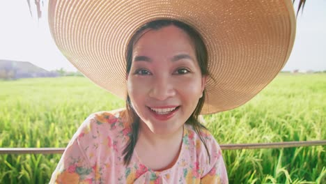 Woman-in-hat-on-video-call-showing-rice-field-with-happy-day-in-summer