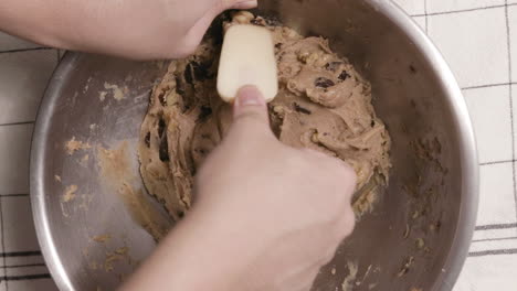 Person-Mixing-Cookie-Dough-Using-Spatula-On-Stainless-Bowl