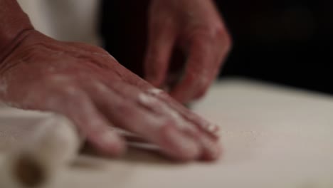 Hand-rolling-dough-to-make-stuffed-Chinese-gyoza-dumplings---isolated-on-hands-and-rolling-pin