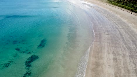 Aerial-drone-following-along-the-shoreline-coastline-of-stunning-Maitai-Bay,-Karikari-Peninsula,-Northland,-New-Zealand-Aotearoa