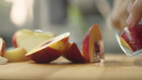 Junger-Mann-Schneidet-Einen-Pfirsich-Auf-Einem-Holztisch-In-Der-Küche,-Um-Einen-Fruchtmilchshake-Zuzubereiten