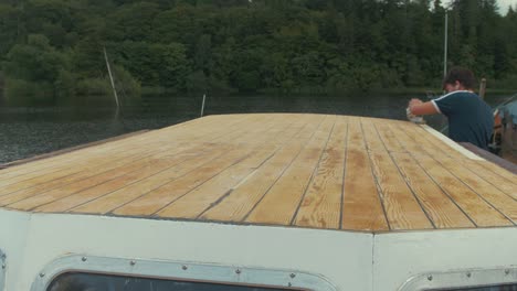Young-man-wipes-down-freshly-sanded-wooden-boat-roof