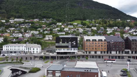 Voss-gondol---Modern-gondola-cable-car-from-Voss-city-center-up-to-mount-Hangurstoppen-Norway---Forward-moving-aerial-showing-ground-station-with-logo-and-gondola-carts-hanging-in-the-air-behind