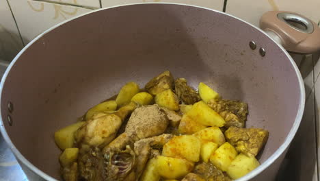 Spices-Being-Poured-Over-Potatoes-And-Sizzling-Chicken-Pieces-In-Cooking-Pot