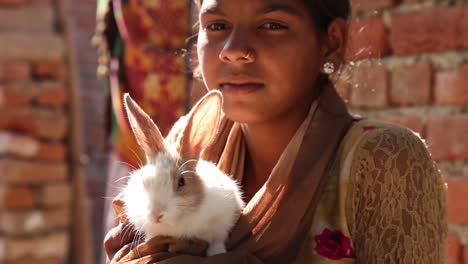 Portrait-of-young-Indian-woman-holding-small-rabbit-in-hands,-Rajasthan