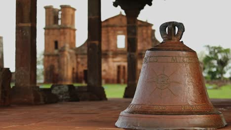 Focus-pull-from-a-brass-bell-in-the-foreground-with-the-Sao-Miguel-Das-Missoes-Jesuit-mission-in-the-background-use-the-link-for-descriptions-location:-Sao-miguel-das-Missoes-date-october-21-2021