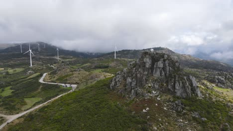 People-on-Caramulinho-viewpoint-and-wind-turbines-in-rural-mountain-landscape,-Caramulo-in-Portugal