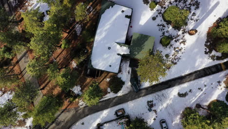 Vehicle-leaving-modern-house-in-woods-in-winter-season,-aerial-top-down-view
