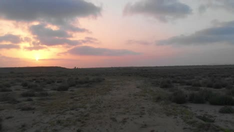 Aerial-Low-Flying-Along-Dirt-Path-In-The-Balochistan-Landscape-Against-Orange-Yellow-Sunset-Skies
