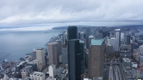 Wide-aerial-shot-pulling-away-from-Seattle's-looming-skyscrapers-on-a-wet-and-cloudy-day