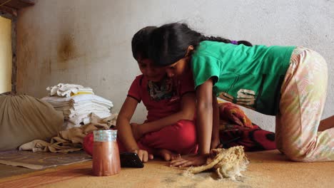 Young-Indian-Girl-Kneels-Beside-Brother-Watching-Online-Video-Content-Smartphone