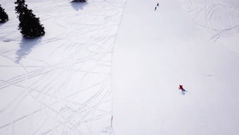 4k-aerial-footage,-drone-following-skiers-on-ski-slope-in-skiing-region