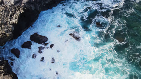 Drone-looking-straight-down-at-crashing-waves-over-rocks-at-Dragon's-Teeth-in-Maui,-Hawaii