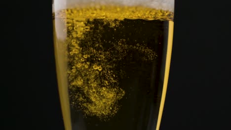 Nahaufnahme-In-Zeitlupe,-Die-Langsam-Champagner-Auf-Die-Flöte-Vor-Schwarzem-Hintergrund-Gießt