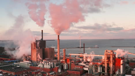 EPIC-establishing-AERIAL-of-a-polluting-coastal-factory-in-Sweden-at-sunset