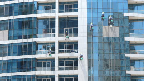 Window-cleaners-working,-dangerous-job,-tall-glass-skyscraper-building