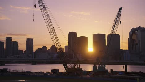 Construction-Cranes-with-Osaka-City-in-Background-at-Sunrise,-Japan