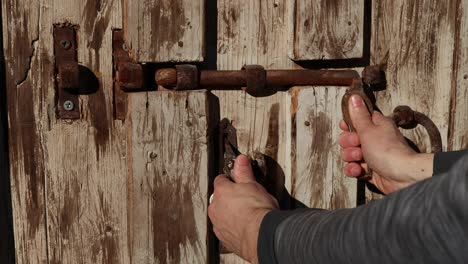 using-an-old-metal-opening-mechanism-to-open-a-wooden-door,-close-up-shot