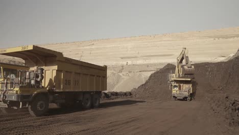 Dump-Truck-Reversing-At-Opencast-Mine-In-Pakistan-With-Excavator-In-Background