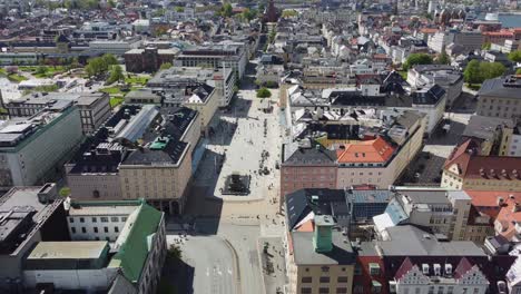 Torgallmenningen-Bergen-reverse-aerial-at-sunny-summer-day---happy-people-walking-below---With-solar-flare-and-tilt-up-to-reveal-beautiful-city-panoramic-view-in-end---Norway