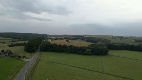 A-4K-drone-shot-flying-over-Ringinlow-road-in-the-Peak-District-near-Sheffield,-the-sky-is-cloudy-and-green-fields-are-on-wither-side-of-a-long,-straight-road