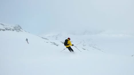 Man-in-yellow-jacket-ski's-down-a-mountain-on-a-cloudy-day-in-Laax,-Switzerland