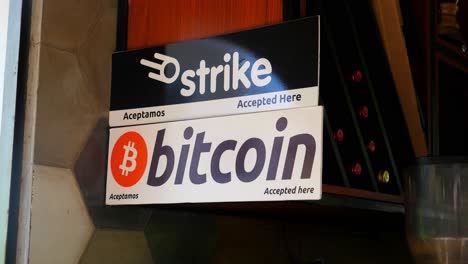 Medium-shot,-a-placard-with-a-bitcoin-sign-hanging-on-the-side-of-the-wall-on-the-bitcoin-beach-in-El-Salvador-Mexico