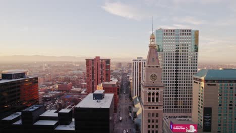 Drone-Aerial-View-Flying-Through-Downtown-Skyline-In-Denver-Colorado-Showing-Lannies-Clocktower-And-Arapahoe-Street-During-Golden-Hour-Sunset