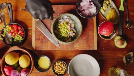 Zubereitung-Von-Ceviche---Tischansicht-Eines-Geschickten-Kochs,-Der-Frische-Rote-Zwiebeln-Hinzufügt-Und-Olivenöl-In-Die-Zutatenschüssel-Gießt,-Sich-Auf-Eine-Traditionelle-Peruanische-Vorspeise-Vorbereitet,-Kochszenenkonzept