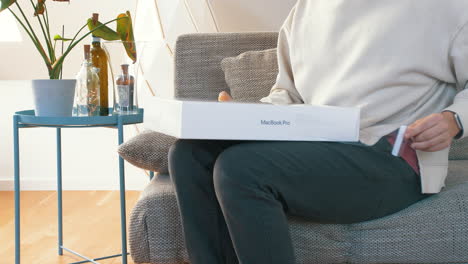 Person,-Die-Auf-Der-Couch-Sitzt-Und-Die-Neue-M1-Macbook-Pro-Box-Auspackt-Und-Plastik-Abzieht