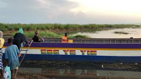 Afrikanische-Menschen-Besteigen-Bei-Sonnenuntergang-Ein-Großes-Holzboot,-Salaga