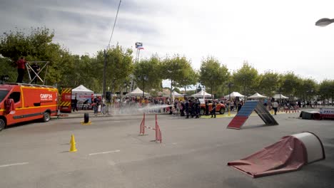 Paramedics-and-firefighters-at-a-fire-prevention-event-with-TV-news-van,-dog-obstacle-course,-Pan-left-shot