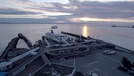 Drone-fly-above-big-white-ferry-boat-British-Columbia-terminal-at-sunset,-scenic-seascape