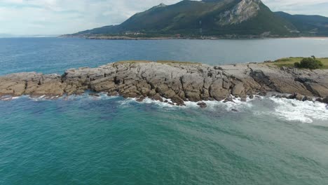 Schaumige-Meereswellen-Treffen-Auf-Die-Felsige-Küste-Spaniens-Mit-Majestätischer-Landschaft-Im-Hintergrund,-Luftaufnahme