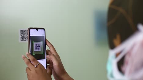 Female-employee-scans-barcode-to-register-attendance-using-smartphone-and-app